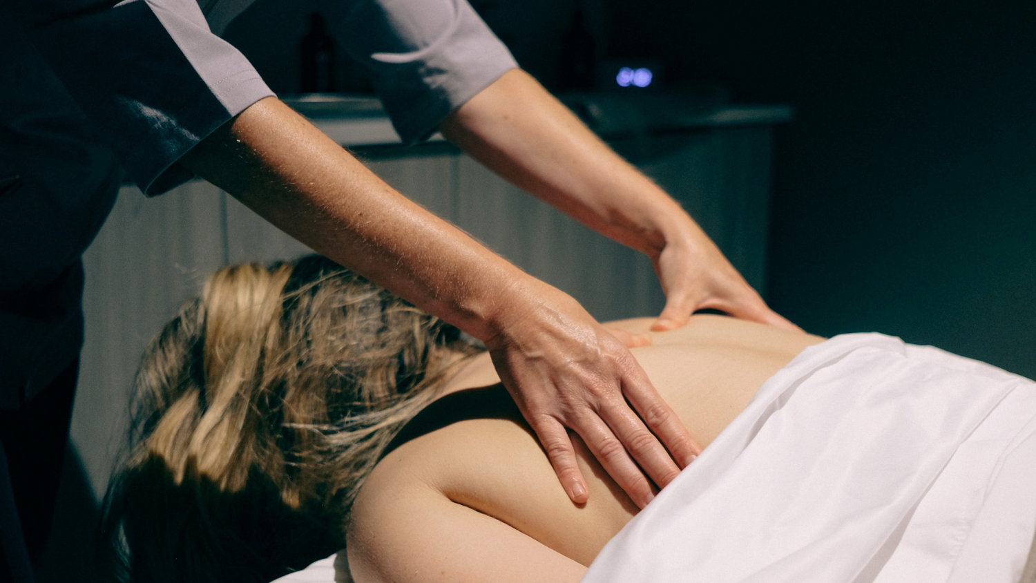 Hands of a person giving another person a back massage in a spa room